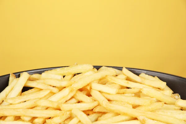 stock image Potatoes fries in the pan on yellow background close-up