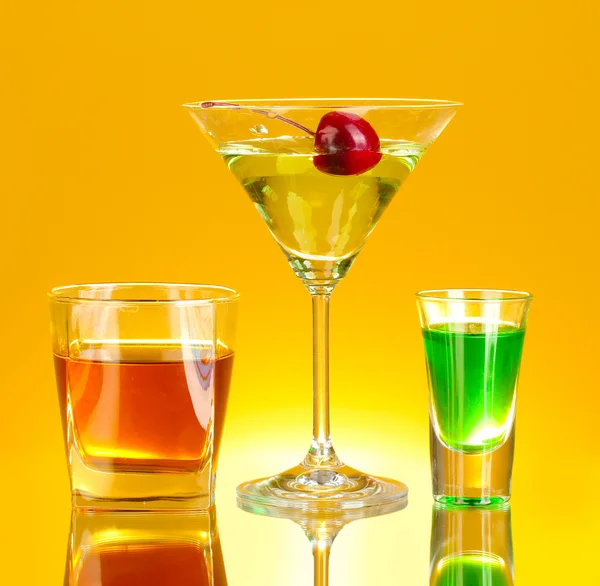 Eine Vielzahl alkoholischer Getränke auf gelbem Hintergrund — Stockfoto