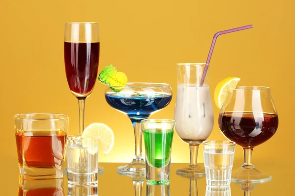 Uma variedade de bebidas alcoólicas sobre fundo amarelo — Fotografia de Stock