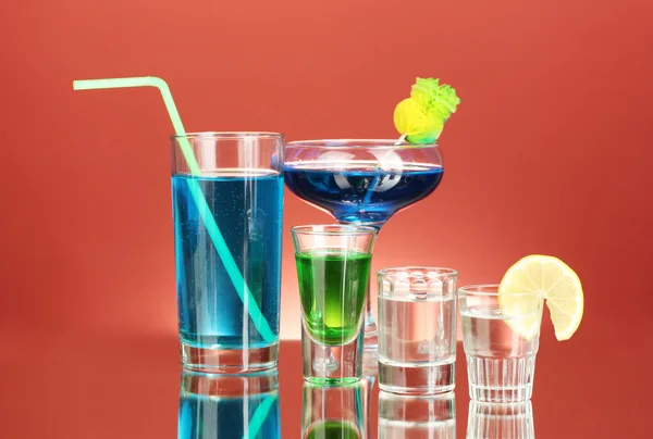 Различные алкогольные напитки на красном фоне — стоковое фото