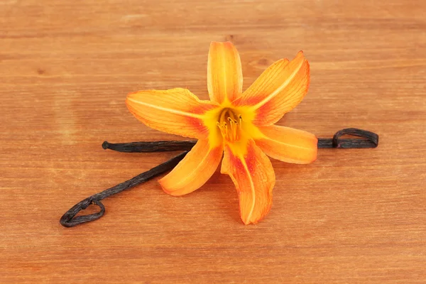 Ο λοβός της βανίλιας με λουλούδι σε ξύλινα φόντο — Φωτογραφία Αρχείου