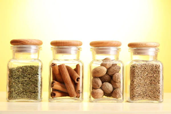 Pulver kryddor i glasburkar på gul bakgrund — Stockfoto