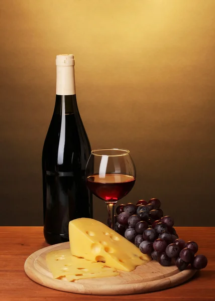 Botella de gran vino con vino y queso sobre mesa de madera sobre fondo marrón — Foto de Stock