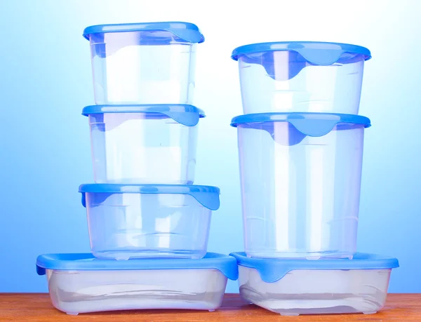 Contenitori di plastica per alimenti su tavolo di legno su sfondo blu — Foto Stock