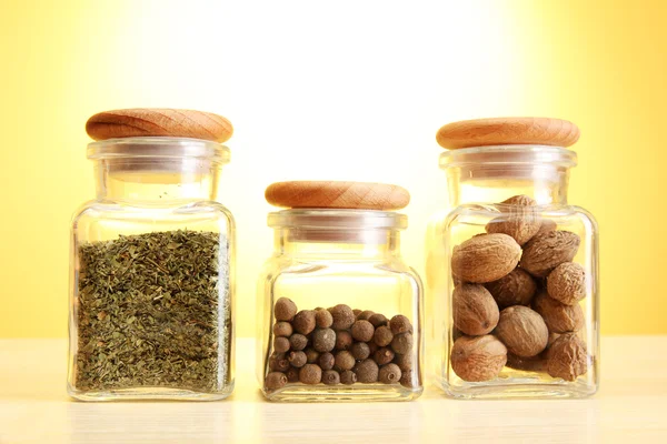 Powder spices in glass jars on yellow background — Stock Photo, Image