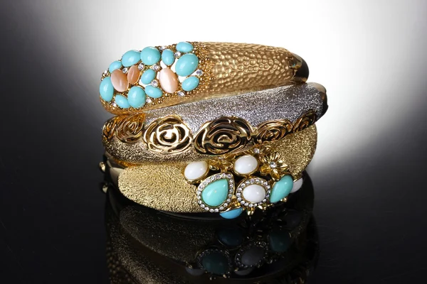 Beautiful golden bracelets on grey background — Stock Photo, Image