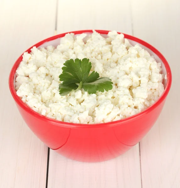 Cottage cheese with parsley in red bowl on white wooden table close-up — Stock Photo, Image
