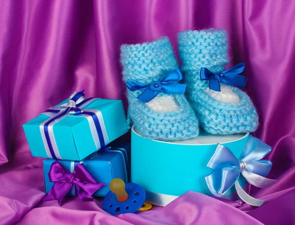 Μπότες μωρό μπλε, πιπίλα, δώρα σε μετάξι φόντο — Φωτογραφία Αρχείου