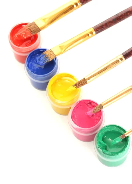 Brushes on the jars with colorful gouache on white background close-up — Stok fotoğraf