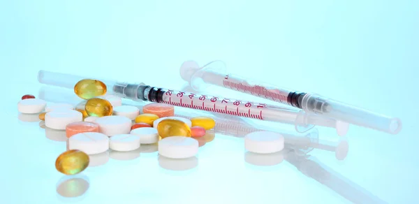 Inzulinové stříkačky s lékařskou ampulí a tablety na modrém pozadí — Stock fotografie