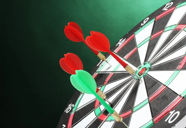 Dart board met darts op groene achtergrond — Stockfoto
