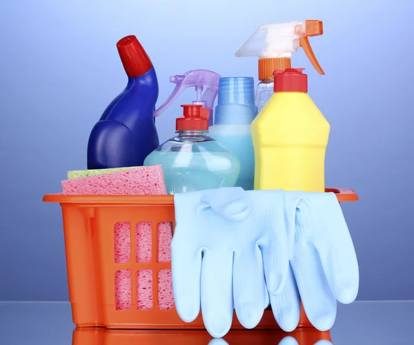 Cesta com itens de limpeza em fundo azul — Fotografia de Stock
