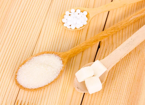 Adoçante e açúcar branco em colheres sobre fundo de madeira — Fotografia de Stock