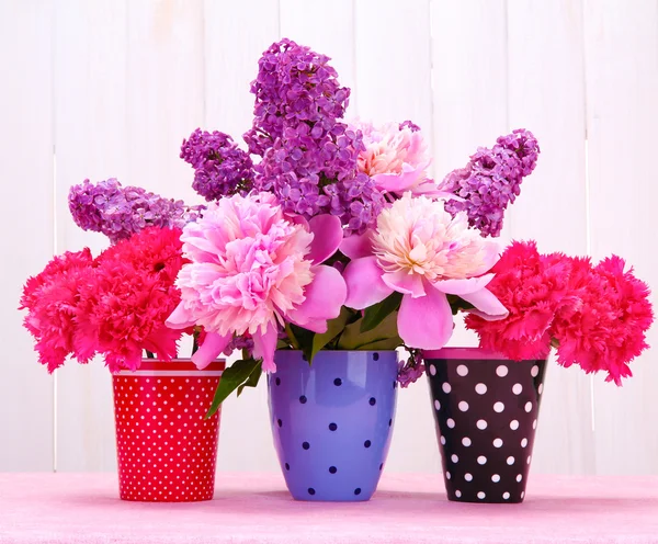 Spring flowers in cups on table on white wooden background — Stock Photo, Image