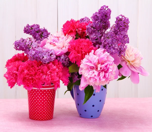 Весенние цветы в чашки на столе на белом деревянном фоне — стоковое фото