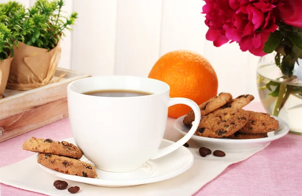 Šálek kávy, cukroví, oranžové a květiny na stole v kavárně — Stock fotografie