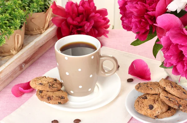 Чашка кофе, печенье и цветы на столе в кафе — стоковое фото