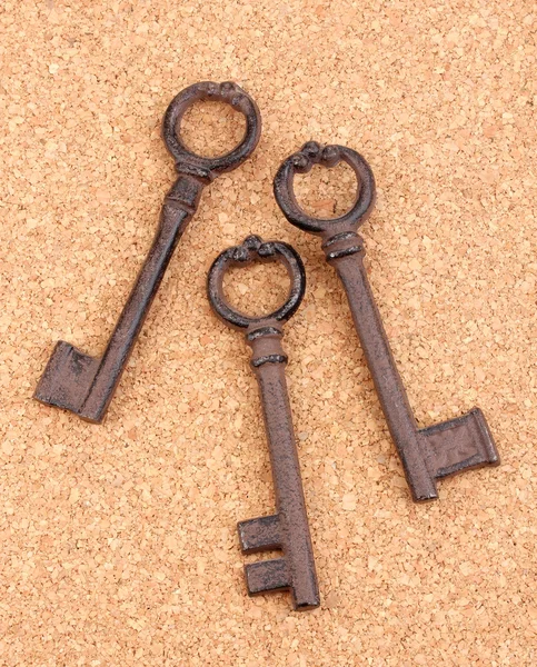 Un montón de llaves antiguas sobre fondo de corcho — Foto de Stock