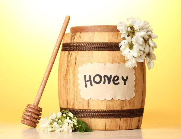 Солодкий мед в бочці з квітами акації на дерев'яному столі на жовтому фоні — стокове фото