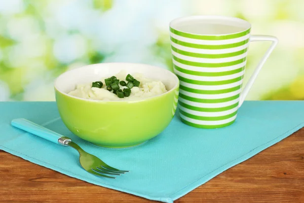 Geprakte aardappel in de kom en cup met melk op kleurrijke servet op houten achtergrond — Stockfoto