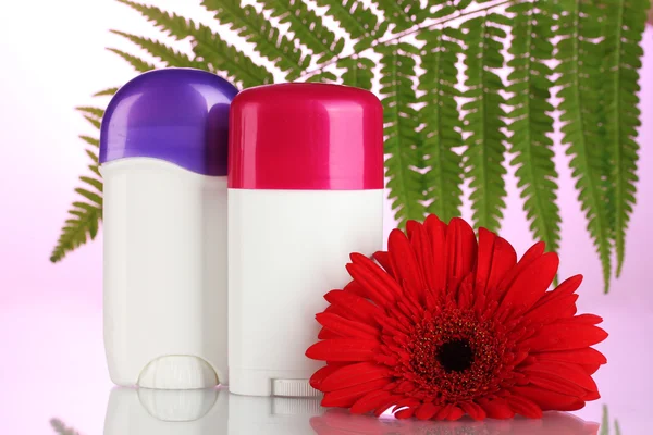 Deodorants with flower and green leaf on pink background — Stock Photo, Image