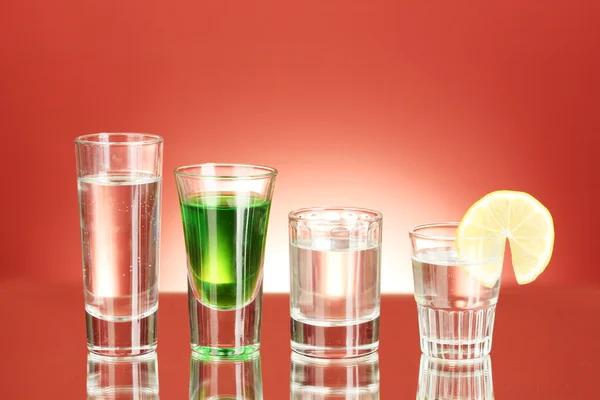 Szeroki wybór napojów alkoholowych na czerwonym tle — Zdjęcie stockowe