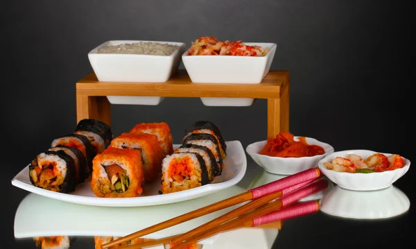 Вкусные суши на тарелке, палочки, соевый соус, рыба и креветки на сером фоне — стоковое фото