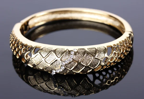 Beautiful golden bracelet with precious stones on grey background — Stock Photo, Image
