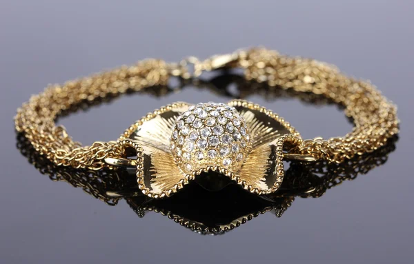 Bellissimo braccialetto d'oro con pietre preziose su sfondo grigio — Foto Stock