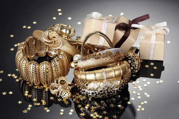 Beautiful golden jewelry and gifts on grey background — Stock Photo, Image