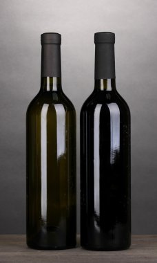 gri zemin üzerine ahşap masa üzerinde büyük şarap şişeleri