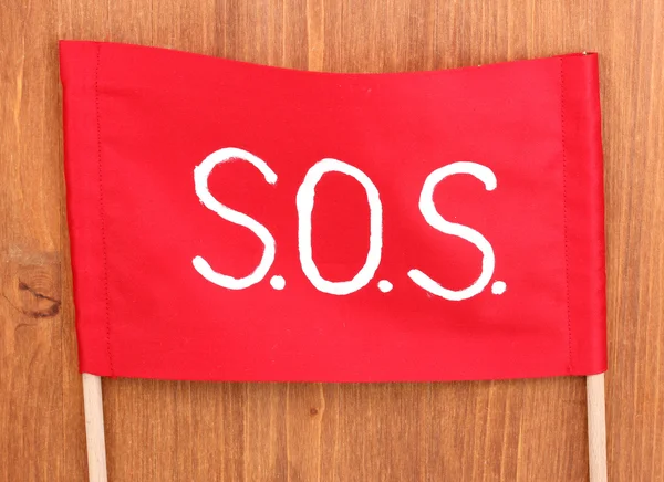 SOS-signaal geschreven op rode doek op houten achtergrond — Stockfoto