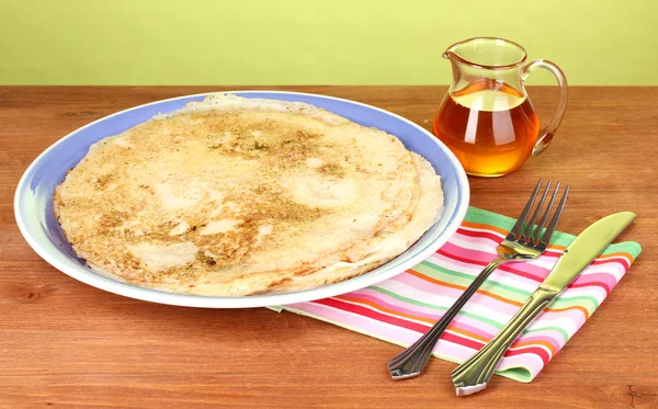 Stack of tasty pancakes on wooden table on green background — Stock Photo, Image