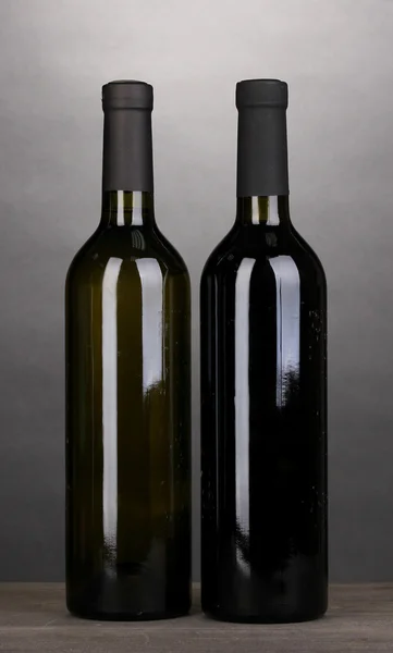 Flessen van grote wijn op houten tafel op grijze achtergrond — Stockfoto