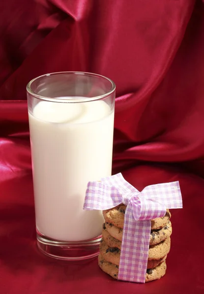 Bicchiere di latte e biscotti su sfondo di stoffa rossa — Foto Stock