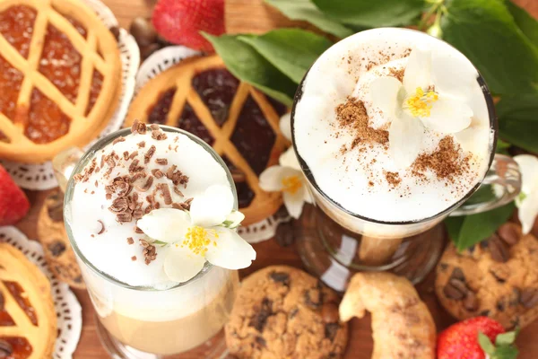 Glasses of coffee cocktail on wooden table with sweet and flowers — Stock Photo, Image