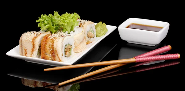 Νόστιμα κυλίνδρους που υπηρέτησε στο λευκό πιάτο με chopsticks απομονώνονται σε μαύρο — Φωτογραφία Αρχείου