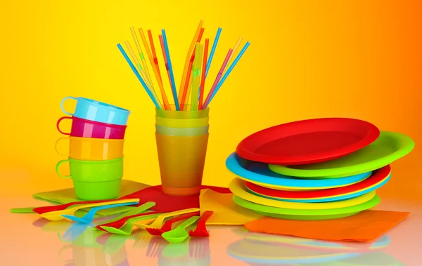 Яскравий пластиковий одноразовий посуд на барвистому фоні — стокове фото