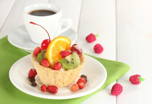 Słodkie ciasto z owocami na płytkę i filiżankę kawy na drewnianym stole — Zdjęcie stockowe