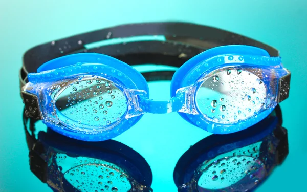 Óculos de natação azuis com gotas no fundo azul — Fotografia de Stock