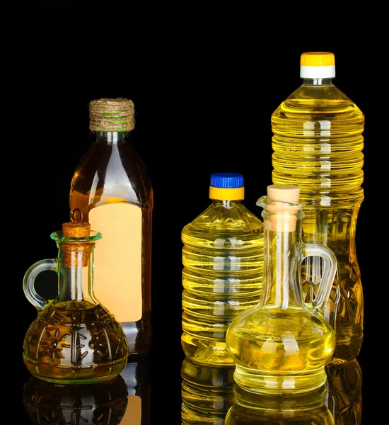 Huile d'olive et de tournesol dans les bouteilles et petites carafes isolées sur fond noir close-up — Photo