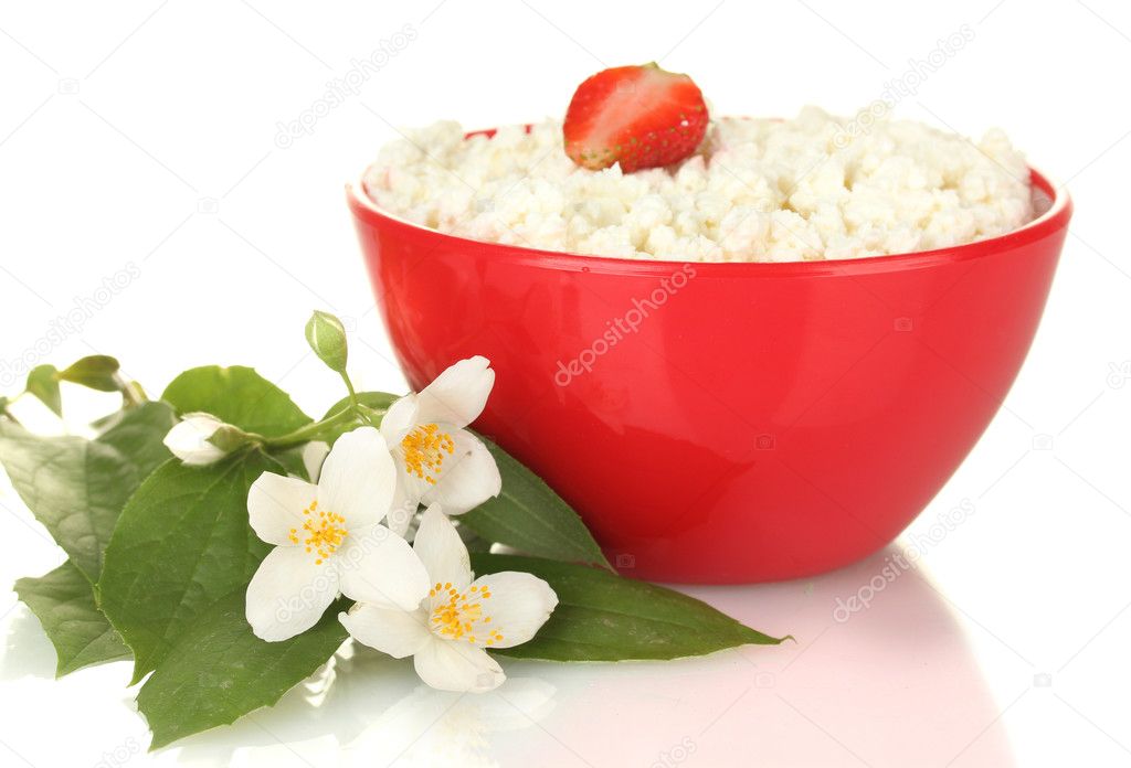 Cottage cheese with strawberry in red bowl and flowers on white background close-up