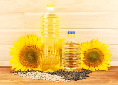 Sunflower oil and sunflower on wood background clipart