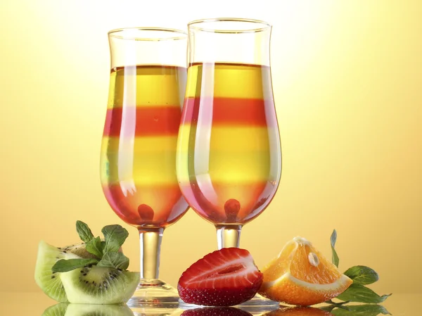 Фруктовое желе в стаканах и фруктах на желтом фоне — стоковое фото