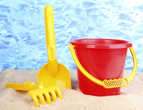 Giocattoli da spiaggia per bambini su sabbia su sfondo acqua — Foto Stock