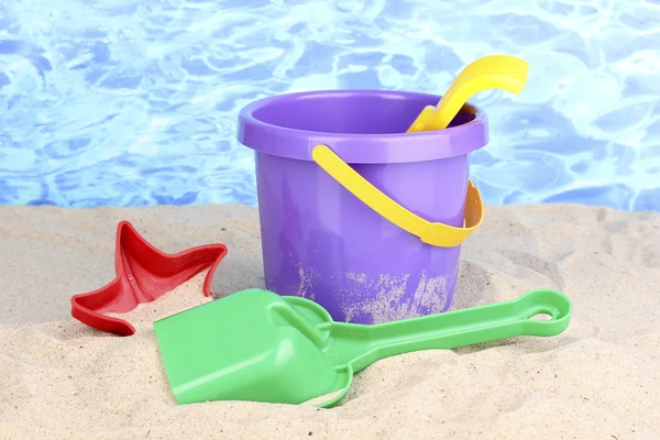 Juguetes de playa para niños sobre arena sobre fondo de agua —  Fotos de Stock
