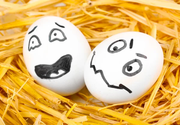 Witte eieren met grappige gezichten in stro — Stockfoto