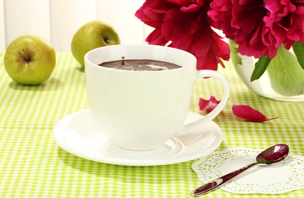 Taza de chocolate caliente, manzanas y flores en la mesa en la cafetería —  Fotos de Stock