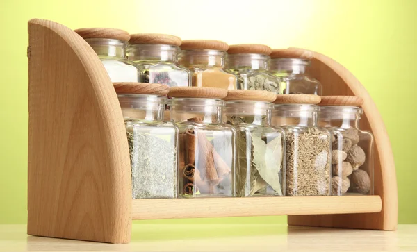 Por fűszerek üvegedények fából készült polcon zöld háttér — Stock Fotó