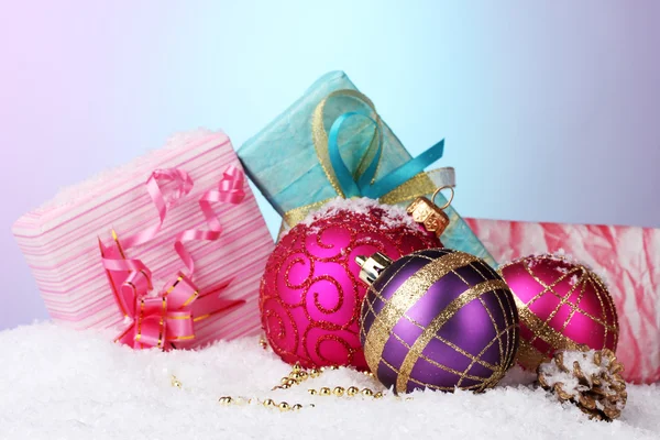 Beautiful Christmas balls and gifts on snow on bright background Stockfoto
